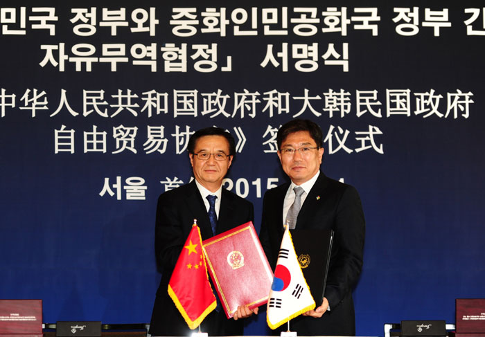 Minister of Trade, Industry and Energy Yoon Sang-jick (right) and Chinese Commerce Minister Gao Hucheng hold an FTA-signing ceremony in Seoul on June 1.