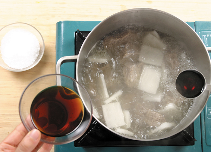 Add the clear soy sauce and salt to taste. It's better to blanch the radishes to reduce their strong smell before adding them to the pot. You can also add potato noodles to the pot, if so desired.