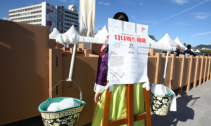 A woman clad in traditional Hanbok attire carries a traditional A-frame on her back that says, “Dada Art Fair,” as she looks around what’s on offer at the Gwangjang Festival on October 17. 