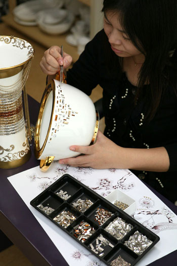 A master artisan accessorizes an article of Prouna chinaware with gem stones. Made with sophisticated crystal work and handmade techniques, Prouna chinaware is known for bringing simple porcelain that is used day to day to a higher, more artistic level.