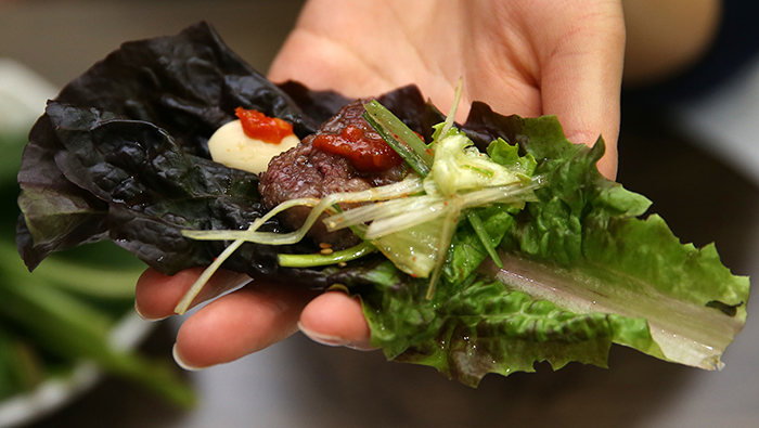 A slice of grilled beef is wrapped in lettuce.