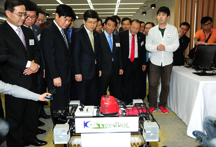 Participants examine an unmanned industrial-grade lawn mower robot at the Sejong Center for a Creative Economy and Innovation.