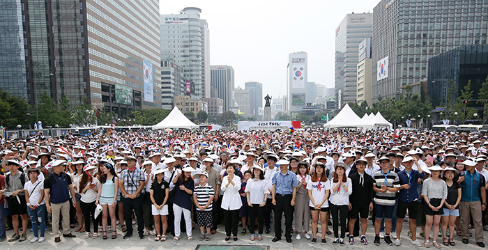 After attending a 70th anniversary ceremony at the Sejong Center for the Performing Arts, President Park Geun-hye (middle) and others create a giant Taegeukgi, the national flag, by wearing different colored caps, at Gwanghwamun Plaza in central Seoul on Aug. 15.