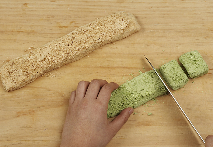 Cut each rice cake loaf into small squares. Add more soybean powder to each individual rice cake square.
