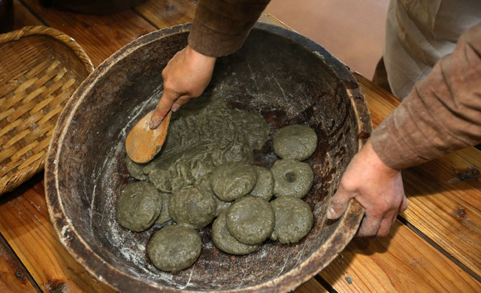 After gathering the <i>omegitteok</i> cakes from boiling water, they are battered with a wooden spoon until no clumps remain.