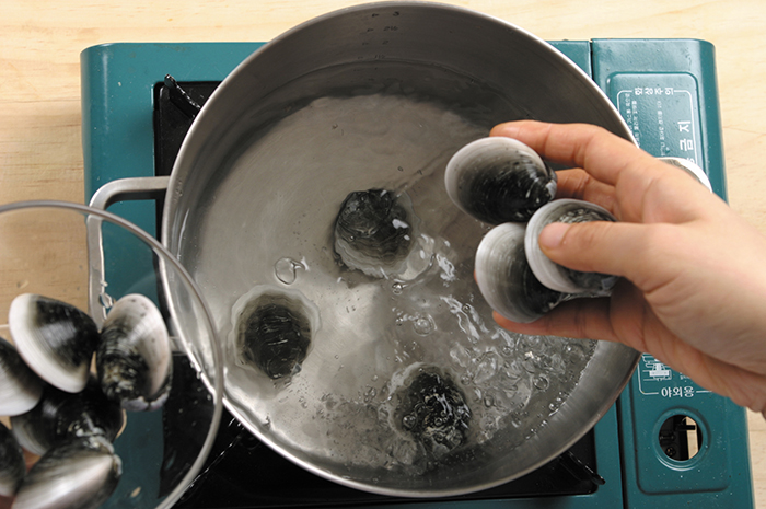Heat the clams and water for 7 minutes over high. When it boils, lower the heat to medium and boil it for another 5 minutes. Make sure to boil the clams in their shells in order to add more flavor to the soup.