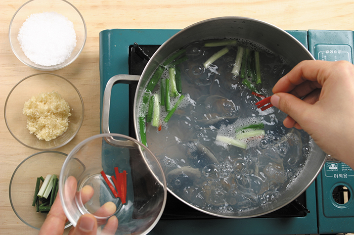 When the clams open, add the shredded green onions, red pepper and minced garlic. Add salt to season. Bring it to boil again.