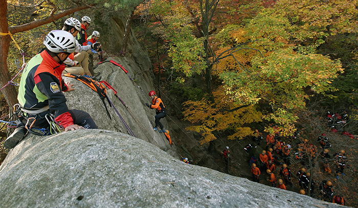 Instructors from the National Park School of Mountaineering Safety observe Gyeonggi Fire Service Academy students train during a rock climbing safety course on October 29. 