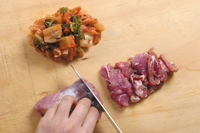 Clean the blood off the pork with a cotton cloth and cut the meat into smaller pieces. Remove the inner seasoning of the cabbage kimchi, and cut it into 2-centimeter long slices. Make sure to use well-ripened kimchi in order to make the dish more delicious.