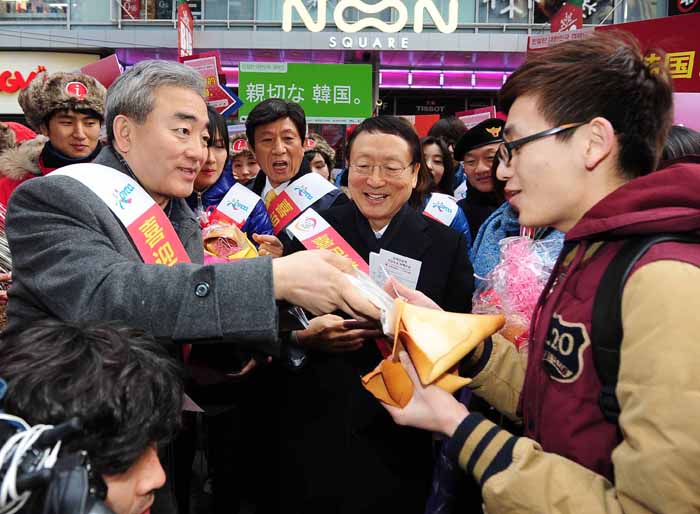 Culture Minister Yoo Jinryong (left) presents a tourist with a fortune cookie during a street campaign in Myeongdong, part of the National Hospitality Campaign for Visiting Foreigners drive on January 29. (Photo: courtesy of the Ministry of Culture, Sports and Tourism)