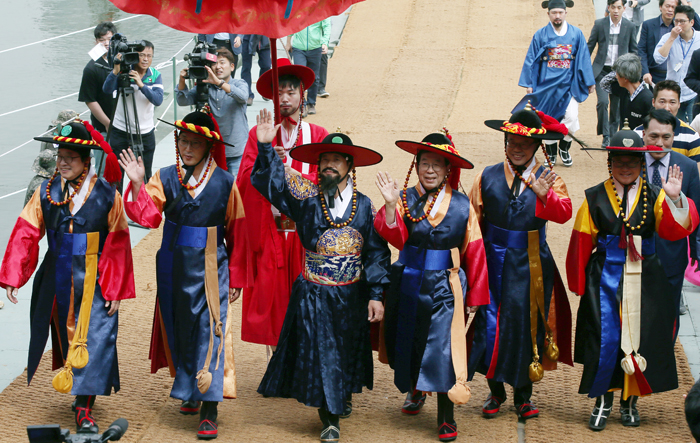 King Jeongjo (third from left), Seoul Mayor Park Won-soon (fourth from left) and other dignitaries cross the <i>baedari</i> temporary bridge that connects the neighborhood of Ichon with Nodeulseom Island in the Hangang River, in Seoul on Sept. 23.