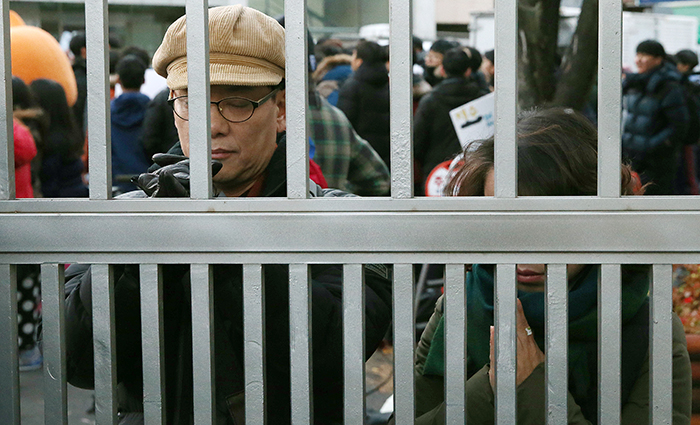 Parents pray in front of the gate as their children enter the test venue to take the CSAT on November 13.