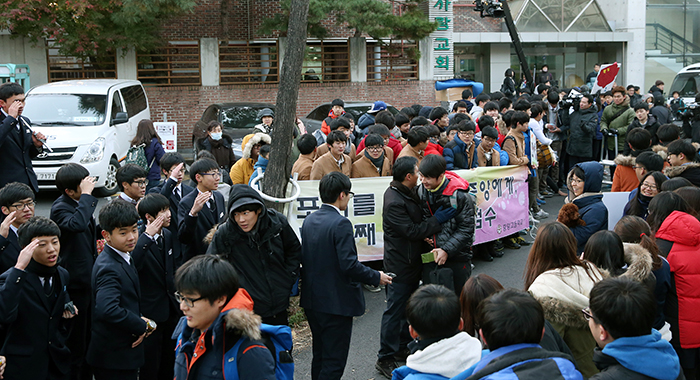 A teacher from Yongsan High School hugs his students, cheering them on, in front of the test venue, Kyungbok High School, on November 13.