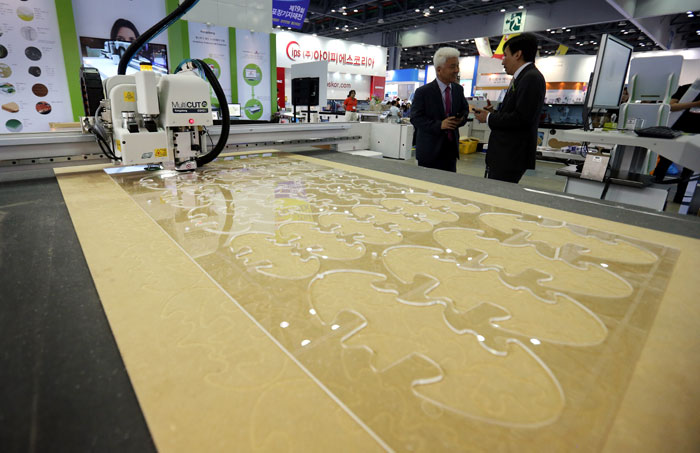 An exhibitor talks with a buyer while demonstrating how to use a digital cutting machine at the Korea Int'l Packaging Exhibition on June 10 at KINTEX in Goyang City, Gyeonggi Province. (photo: Yonhap News)