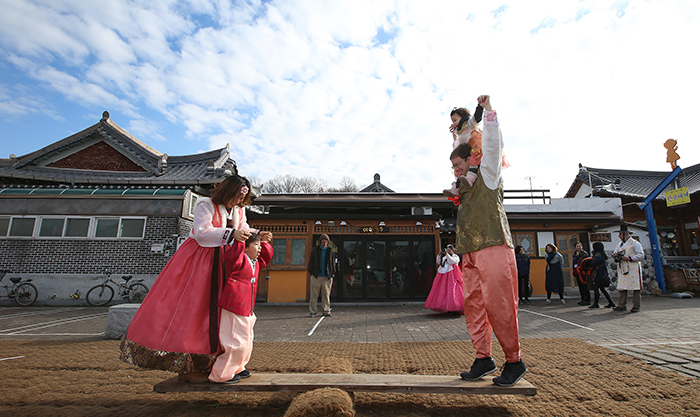 Clad in traditional Hanbok attire, Aaron Snowberger (right) and his family enjoy the <i>neolttwigi</i>, or seesaw, at the Jeonju Hanok Village on Dec. 12.