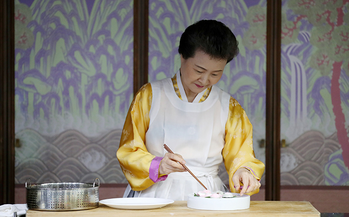 Director Yoon Sook-ja of the Institute of Traditional Korean Food takes the rice cake pieces out of the steamer and places them on the plate.