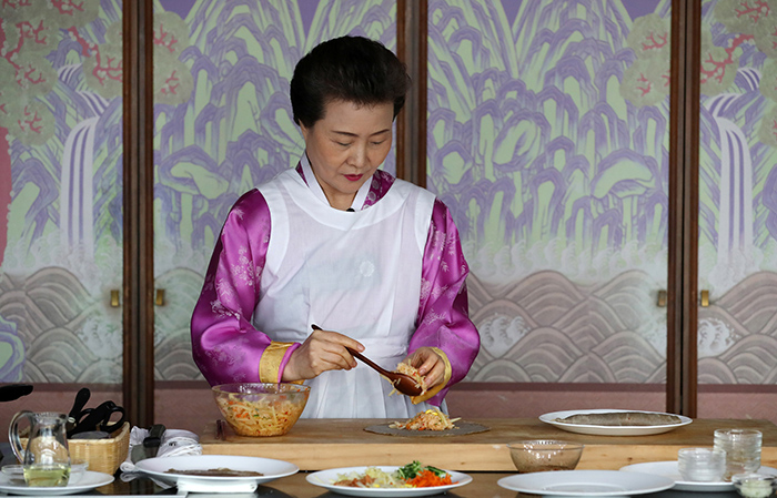 Director Yoon Sook-ja of the Institute of Traditional Korean Food places some bibimbap into a round buckwheat wrap.