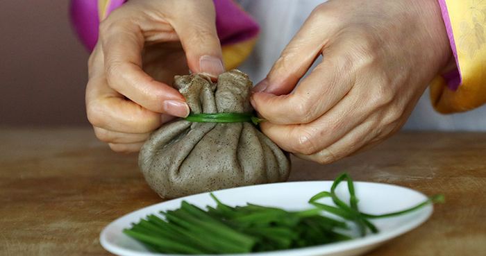Wrap up the remaining bibimbap and tie it with a strip of blanched water parsley so that it's shaped like a pouch.