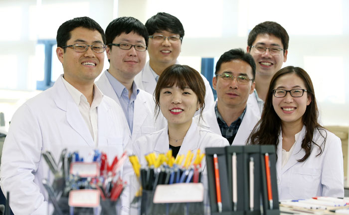 Researchers on the Monami ink development team pose for a photo in front of some Monami products.