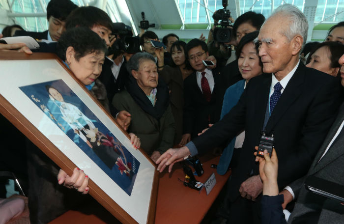 Former Japanese Prime Minister Tomiichi Murayama (right) is offered a painting drawn by one of the victims who was abducted by the Japanese military and forced into sexual slavery during the Second World War, in Seoul on February 13. (photo: Yonhap News)