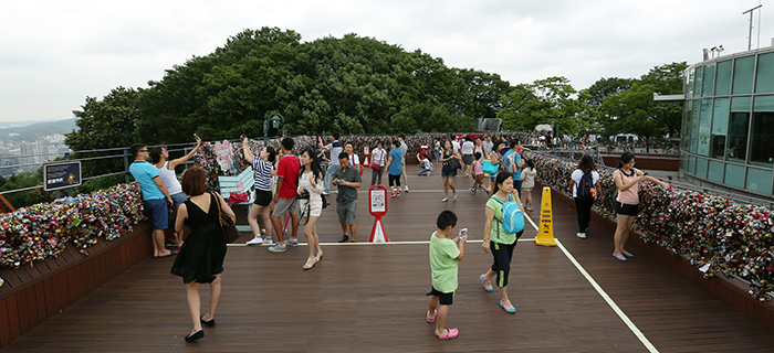Despite the cloudy weather signaling the approach of the monsoon season, many sightseers and tourists visit N Seoul Tower and take photos of themselves and the 'padlocks of love' on July 22. (photo: Jeon Han)