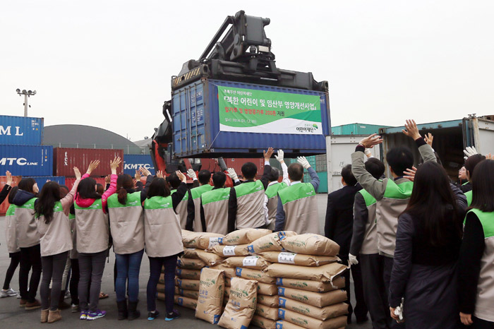 Staff and volunteers at ChildFund Korea wave to the containers at the Port of Incheon on March 12. Loaded with 179 tons of flour and 20 tons of bean flour, these containers will be sent to children, mothers and pregnant women in North Korea. (photo: Yonhap News)