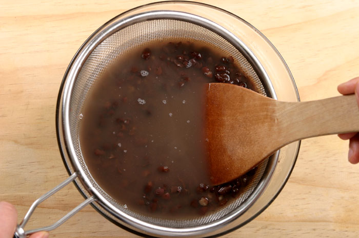 You need to boil the red beans. After boiling, lower the heat and continue to let them boil. Make sure to not burn the beans. Strain the cooked beans. When preparing the five grains in a steamer, it's a good idea to sprinkle in some of the water used to boil the red beans and a bit of salt.