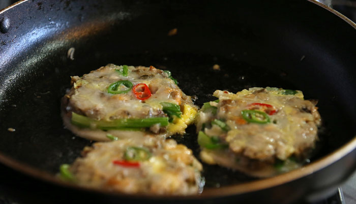 Fry the savory dough cakes for five minutes over medium heat. When the bottom is well-done, flip it, put a lid on the pan and cook it for another 3 minutes.