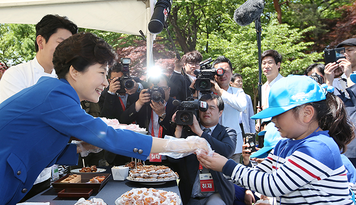 President Park Geun-hye shares some sweet and sour and chicken with children at the chef's career booth in the Nokjiwon Garden of Cheong Wa Dae on May 5.