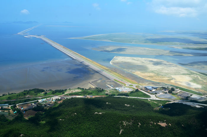The Saemangeum development project is a state-funded land reclamation project. It includes infrastructure, such as ports and roads, and covers an area of 283 square kilometers. It was created by reclaiming the mud flats that stretch between Gunsan, Gimje and Buan in Jeollabuk-do (North Jeolla Province). The Saemangeum tidal flats are located in the center of the greater Yellow Sea area. This is a strategic point that can reach cities in China, Japan and Eurasia within three hours by plane. The above photo shows the Saemangeum Seawall that defines the project. This 33.9-kilometer dyke is the largest seawall of its kind in the world.