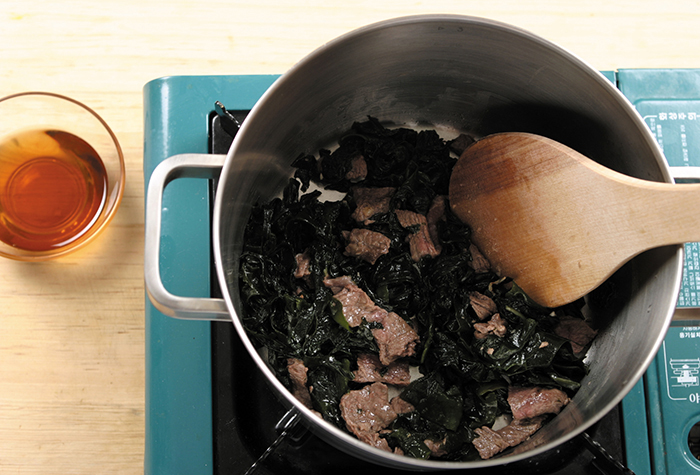 Add some sesame oil to a preheated pot and stir-fry the beef there for 2 minutes over medium. Add soaked seaweed and fry it all together for another 3 minutes.