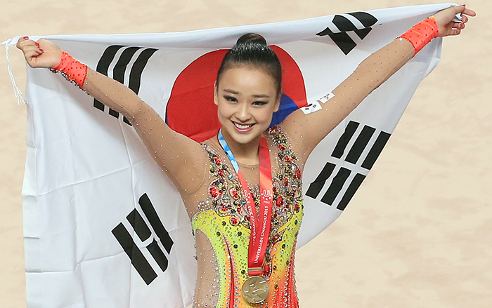 Son Yeon-jae smiles as she unfolds the Taegeukgi, Korea's national flag, after winning her first gold medal at a Universiade in Gwangju.