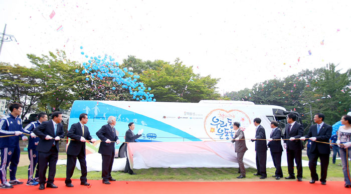 Attendees at the Sports Bus launch ceremony unveil one of the Sports Buses.