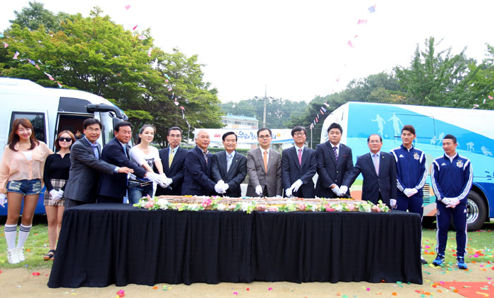 Second Vice Minister of Culture, Sports and Tourism Kim Chong (sixth from right) and other attendees help to cut the long roll of rice cake during the Sports Bus launch ceremony.