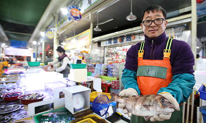 Jeong Gwang-u, owner of Lotto Fisheries in the Tongyeong Jungang Market, shows off a red seabream for sashimi on November 24. 