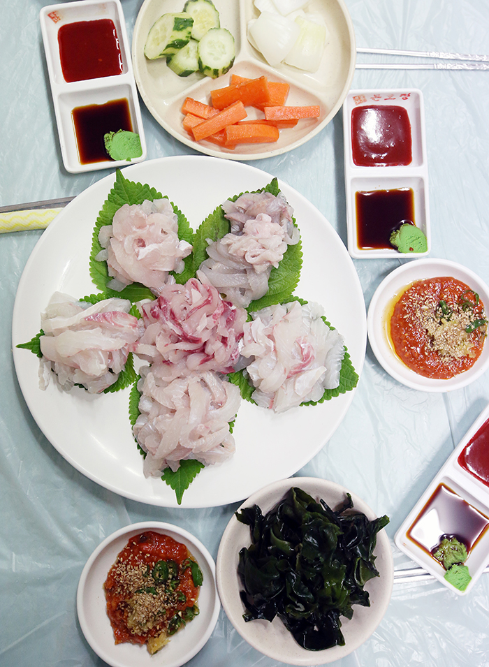  Raw fish bought at the Tongyeong Jungang Market is served in a nearby restaurant at a reasonable price. The restaurant provides assorted vegetables and sauces, too. 