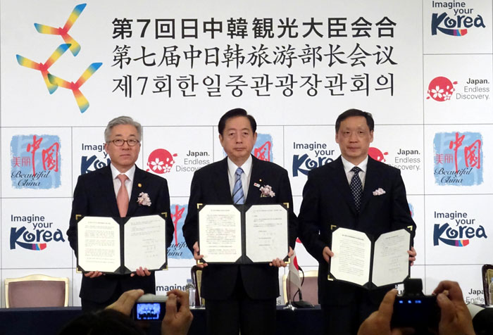 Korea, Japan and China hold the trilateral tourism ministers’ meeting in Tokyo on April 12. In a joint statement, the countries agreed to expand the number of people-to-people exchanges to 30 million by 2020. Minister Kim Jongdeok of Korea (left), Minister of Land, Infrastructure, Transport and Tourism Akihiro Ota (center) and Chairman of the China National Tourism Administration Li Jinzao pose for a photo, joining hands after signing the joint statement.