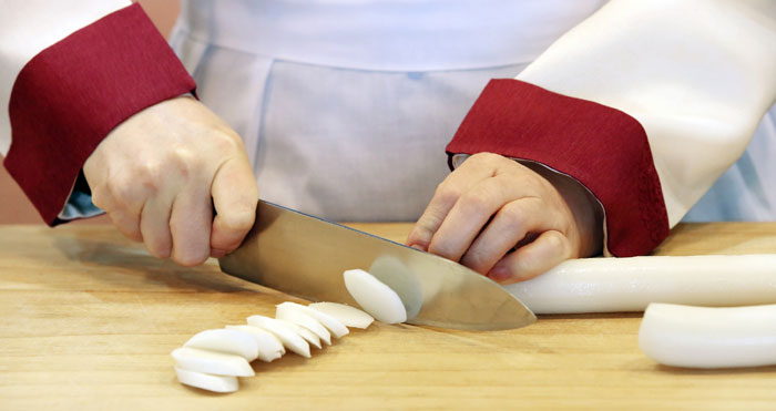 The long <i>garaetteok</i> needs to be sliced into round discs. The round shape of the rice cake represents wishes for good fortune.