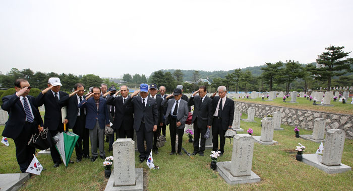 A group of Vietnam War veterans salutes the tomb of one of their fellow soldiers after locating and tending to it.