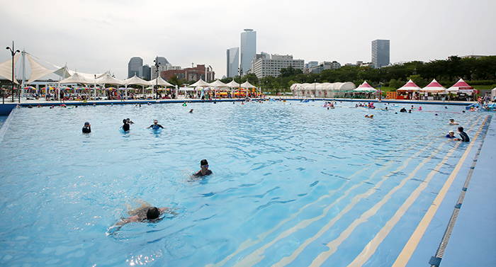 At one of the outdoor swimming pools in Yeouido, people can enjoy water activities while appreciating the view of skyscrapers and the National Assembly.