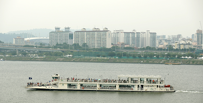 A river cruise ship along the Hangang River steams by a lookout platform at Seonyudo Park. Many people ride the ferry to overcome the sweltering heat. (photo: Jeon Han)