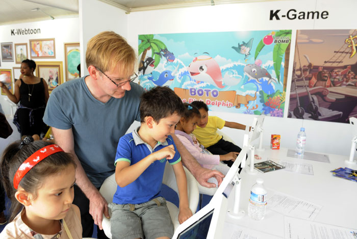 Children enjoy watching cartoons and video games at a booth during the London Korean Festival 2015.