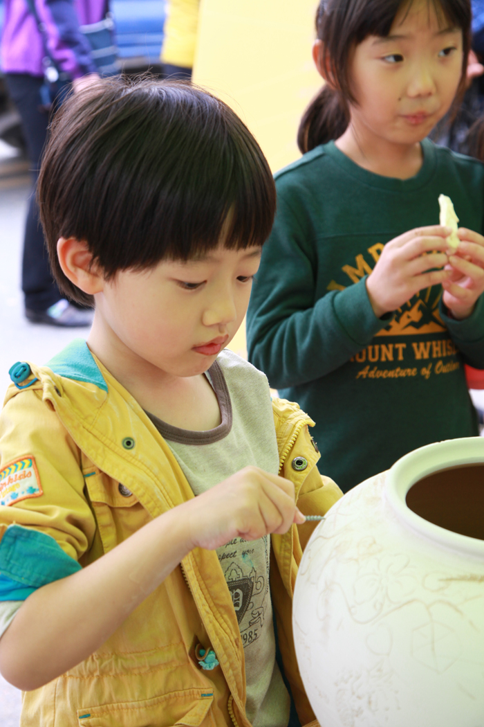 A young potter engraves an inscription on a porcelain vase. 