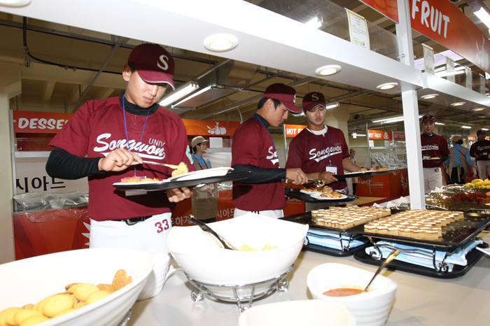 (Top) Practice runs are underway at the registration center at the athletes' village in Gwangju. (Bottom) Athletes sample the fare at one of the village's official restaurants.