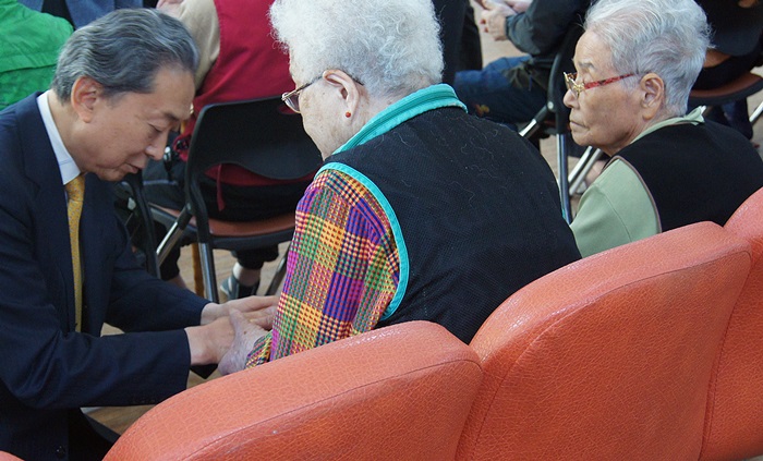 Former Japanese prime minister Yukio Hatoyama, on his knees, offers words of consolation to the surviving victims of atomic bombings at Hapcheon, Gyeongsangnam-do province.