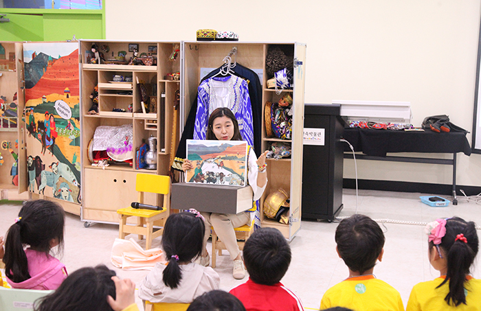 Children listen to an explanation about Uzbek traditions during a class featuring the Uzbekistan Kkureomi Cultural Discovery Box.