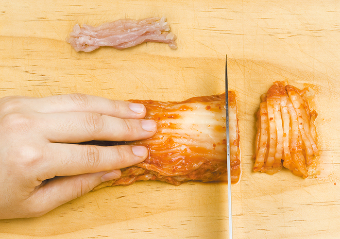 Cut the cabbage kimchi and pork to make the filling for the buckwheat rolled pancakes. Shredded radish kimchi or bean sprouts can also be used.