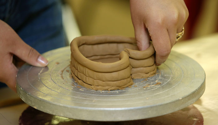 An international student makes a heart-shaped piece of pottery. 