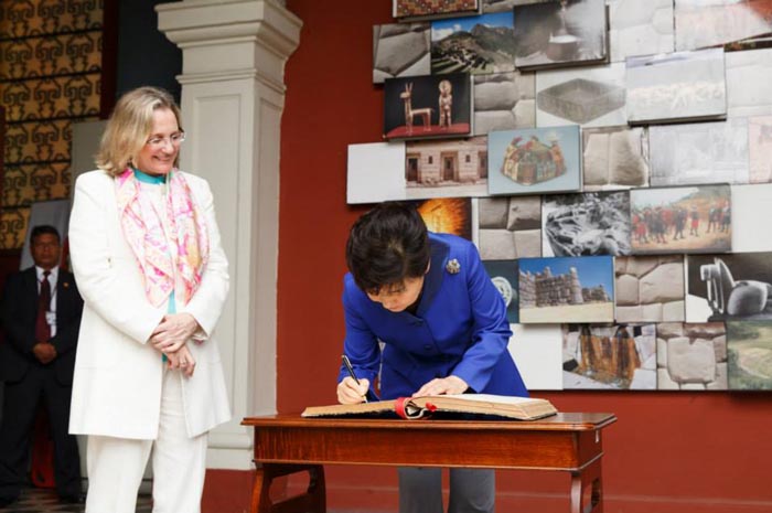 President Park Geun-hye (right) signs the guest book as Peruvian Minister of Culture Diana Alvarez-Calderon looks on.