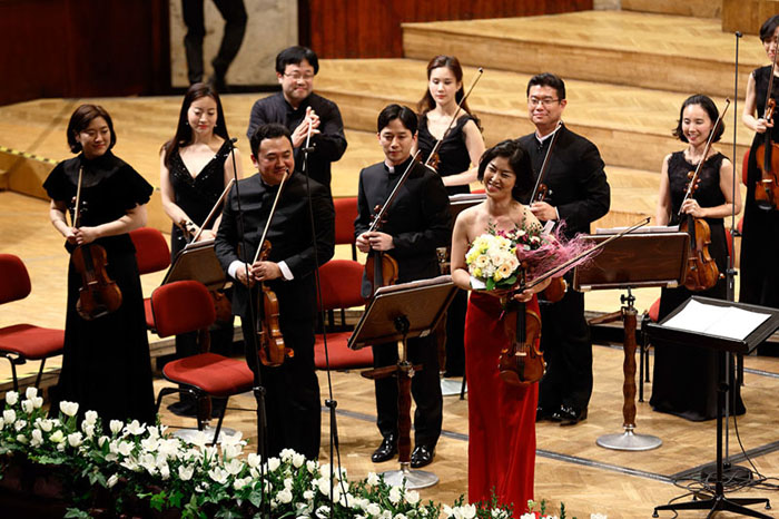(Top) The Korean Chamber Orchestra performs at the National Philharmonic Orchestra Theater in Warsaw on March 25. Violinist Baek Ju-young, holding the bouquets, thanks the audience during the applause.